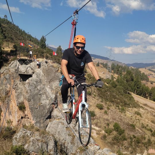 Persona disfrutando de un paseo en Skybike sobre el paisaje montañoso de Cusco, Perú.